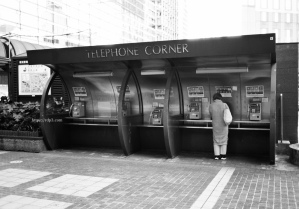 横浜駅前の公衆電話の谷間でスマートフォンを操作する女性　レンズ　COLOR-SKOPAR 35mm F2.5 P II | フィルム　アクロス2